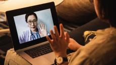 Person waving at doctor on laptop screen